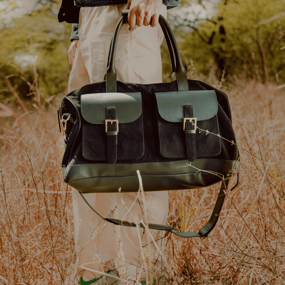 Close-up of Ajax plant leather duffle bag in black and forest green being carried outdoors, highlighting structure and travel use