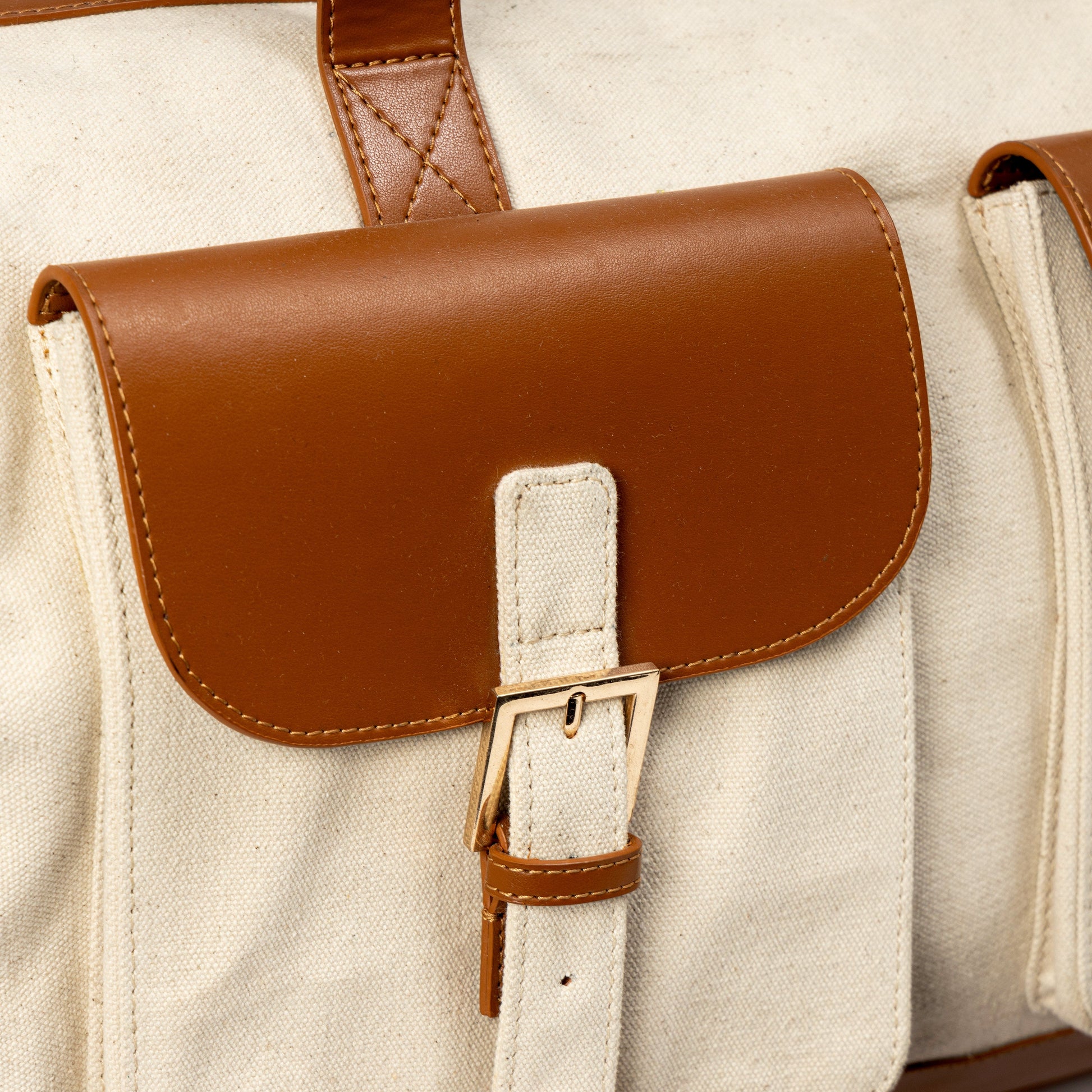 Close-up of Ajax plant leather duffle bag in beige and gingerbread colour showing front pocket detail and buckle design