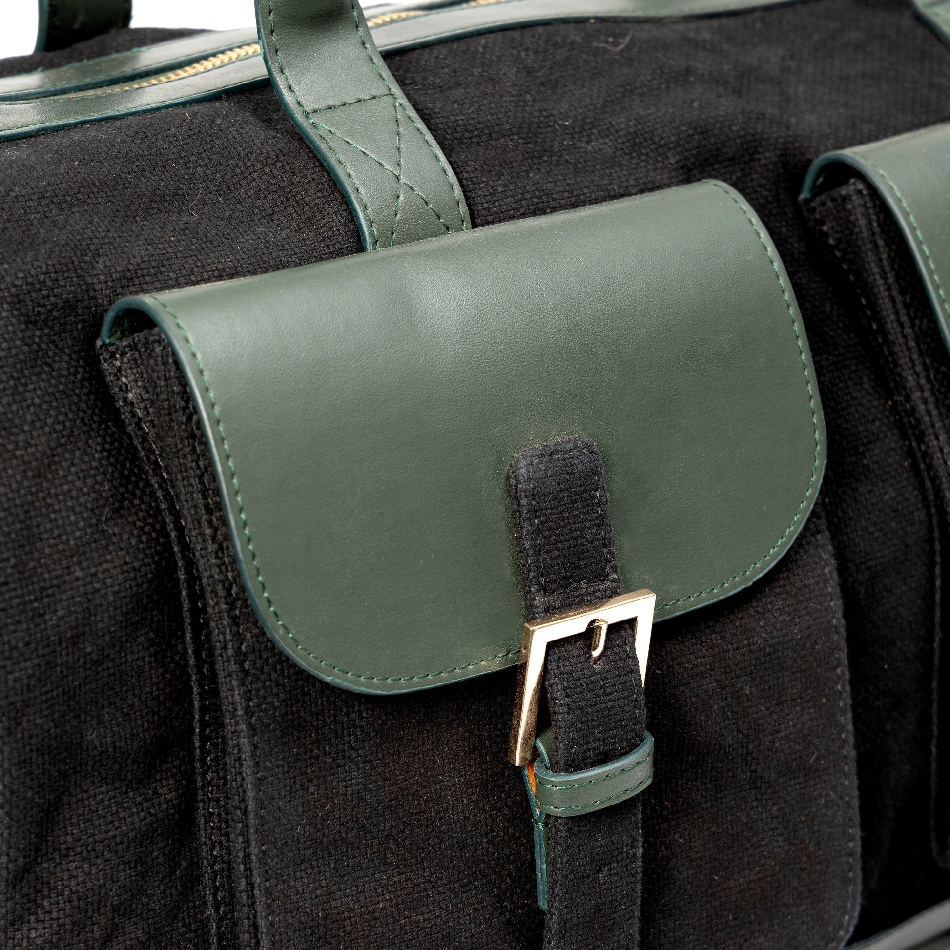 Close-up of Ajax plant leather duffle bag in black with forest green flap pocket and buckle detail showing texture and craftsmanship