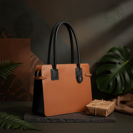 Aranyani plant-based leather tote bag in gingerbread and black colour, structured design with dual handles, placed on a dark surface with natural foliage styling
