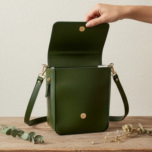 Ceres green plant leather crossbody bag with flap open showing main compartment and inner storage on a neutral surface