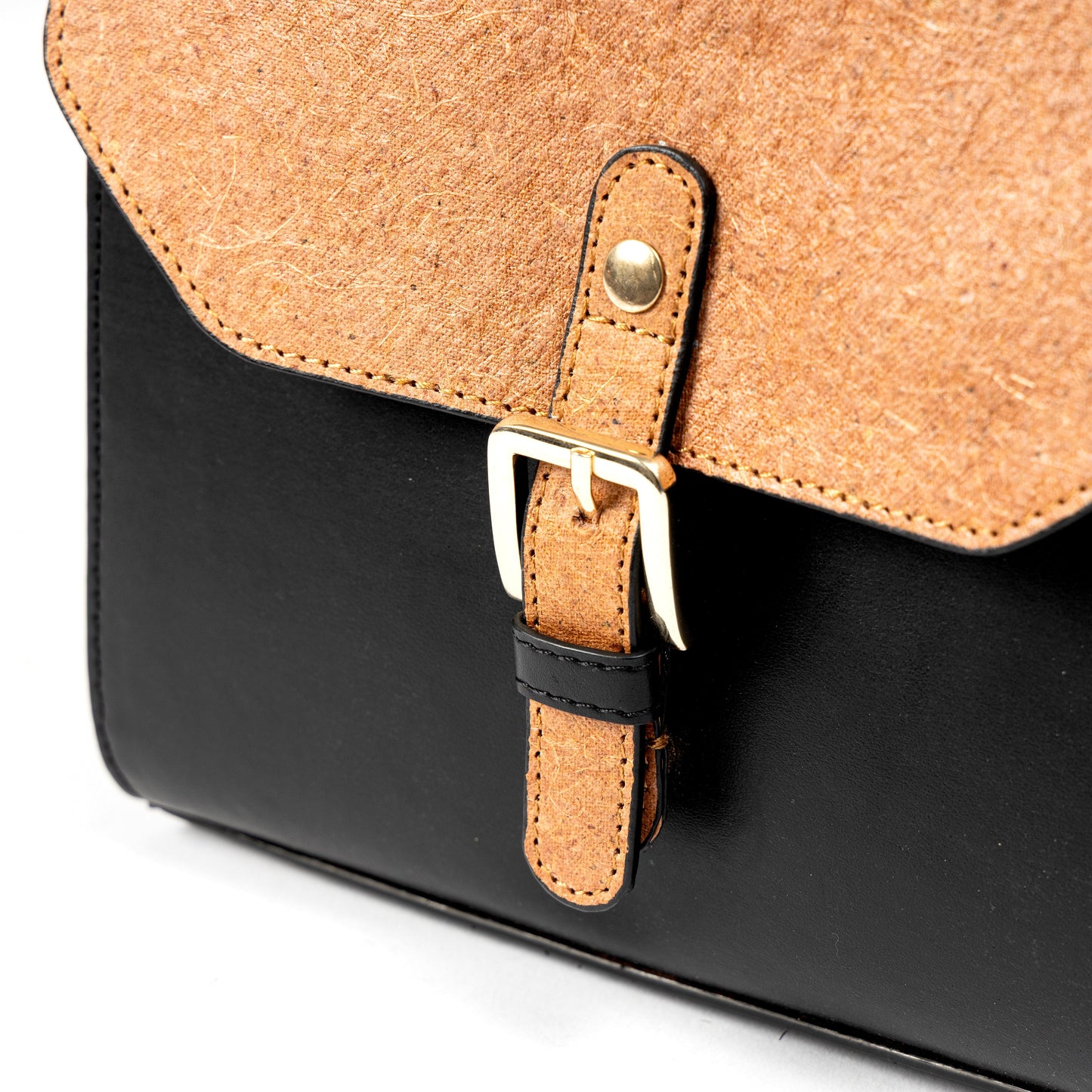 Close-up of buckle closure detail on black and coconut orange plant leather sling bag with gold hardware