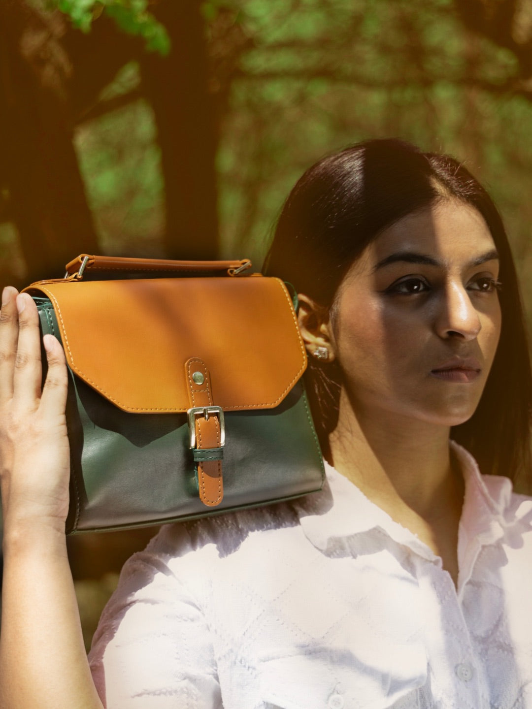 Model holding Juniper Green plant leather sling bag outdoors showcasing structured design and premium craftsmanship by Green Hermitage